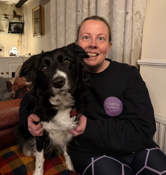 Rebecca sitting next to her dog smiling.