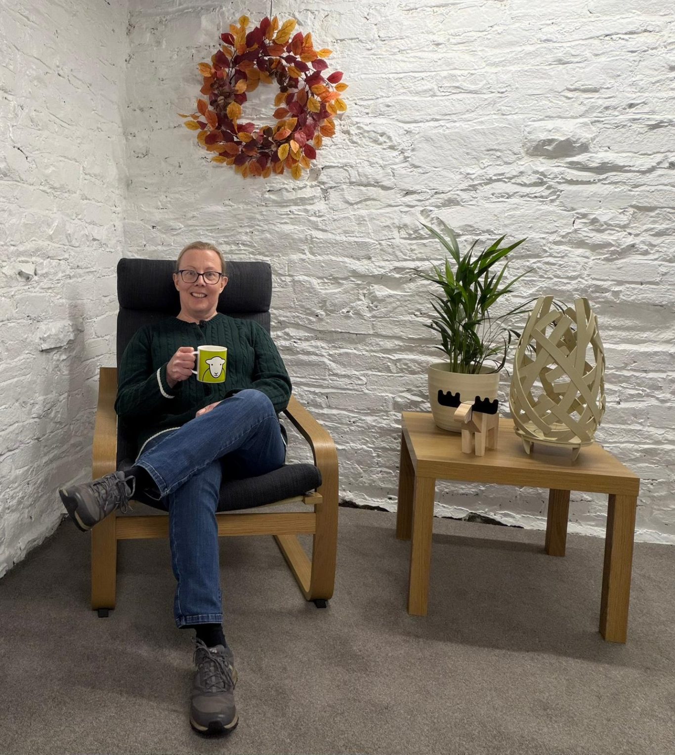 Rebecca is sitting in a chair in her virtual pilates studio, The Wellness Barn.